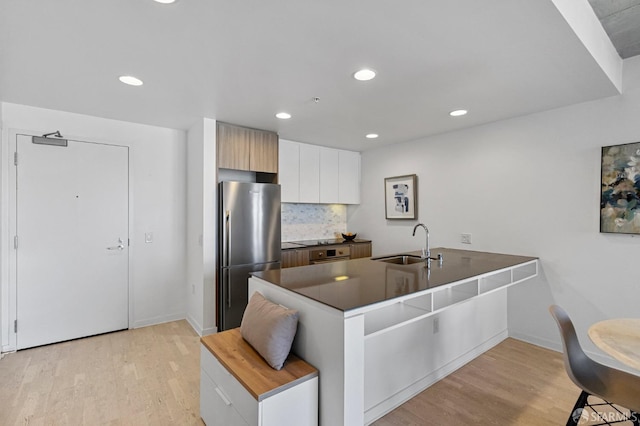 kitchen with light wood-style flooring, modern cabinets, appliances with stainless steel finishes, white cabinetry, and a sink