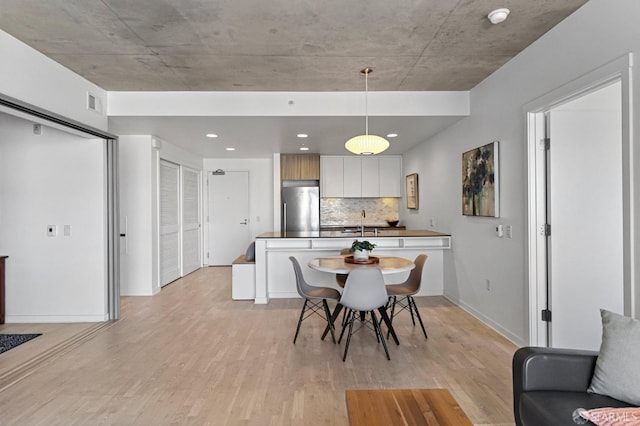 dining space with light wood-style floors, visible vents, and baseboards