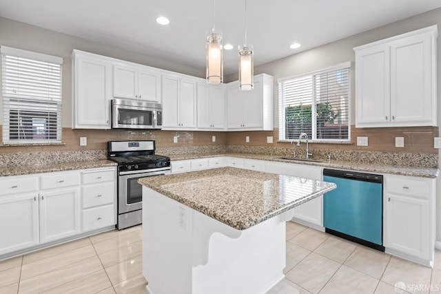 kitchen with sink, white cabinetry, decorative light fixtures, appliances with stainless steel finishes, and a kitchen island