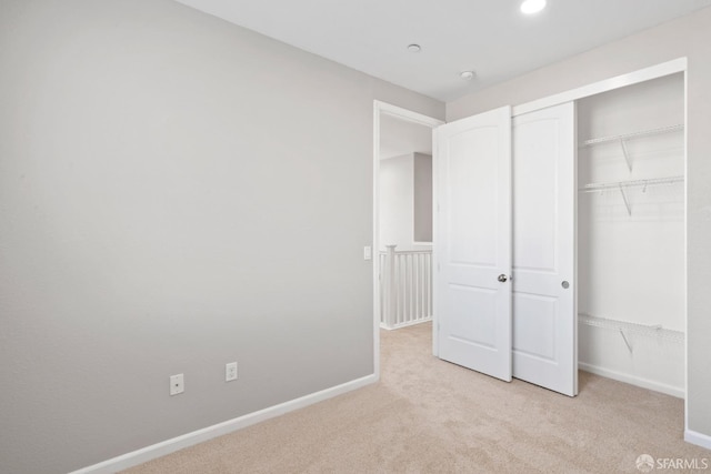 unfurnished bedroom featuring light colored carpet and a closet