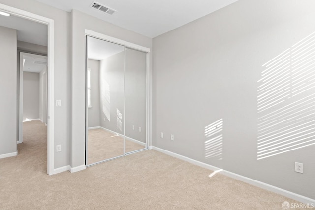 unfurnished bedroom featuring light carpet and a closet