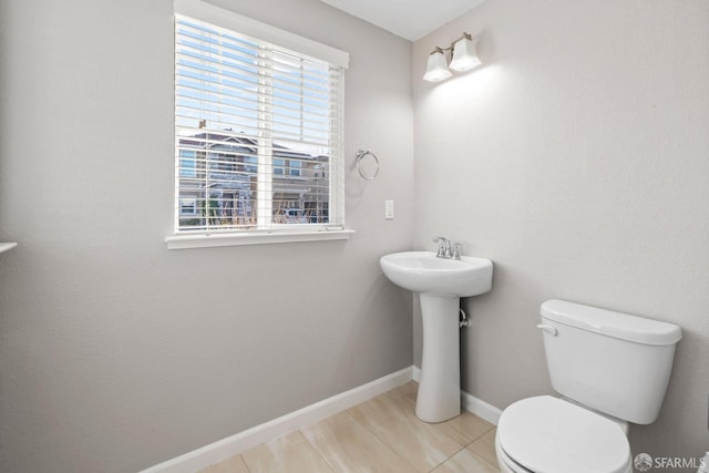 bathroom with toilet, sink, and a wealth of natural light