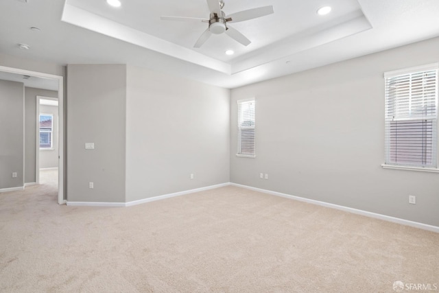 carpeted spare room featuring ceiling fan and a tray ceiling