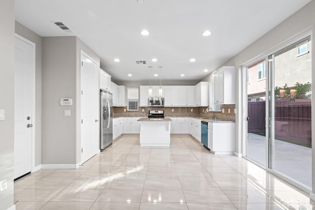 kitchen featuring pendant lighting, appliances with stainless steel finishes, a center island, tasteful backsplash, and white cabinets