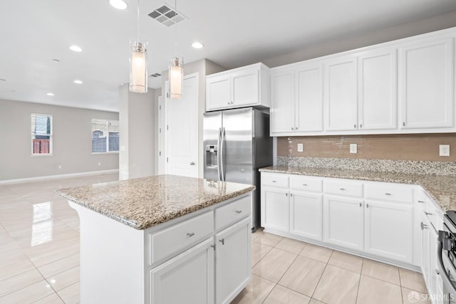 kitchen with pendant lighting, white cabinetry, a center island, tasteful backsplash, and light stone counters