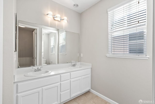 bathroom with tile patterned flooring, vanity, a wealth of natural light, and toilet