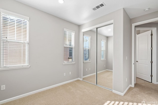 unfurnished bedroom with light colored carpet and a closet