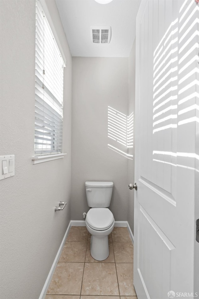 bathroom featuring a healthy amount of sunlight, toilet, and tile patterned flooring