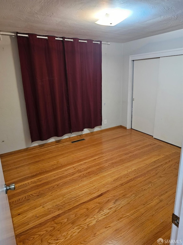 unfurnished bedroom with light hardwood / wood-style floors, a textured ceiling, and a closet