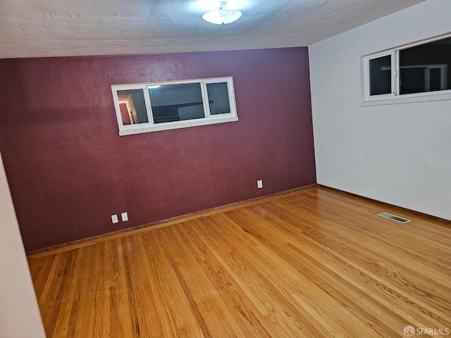 spare room with light hardwood / wood-style floors and a textured ceiling