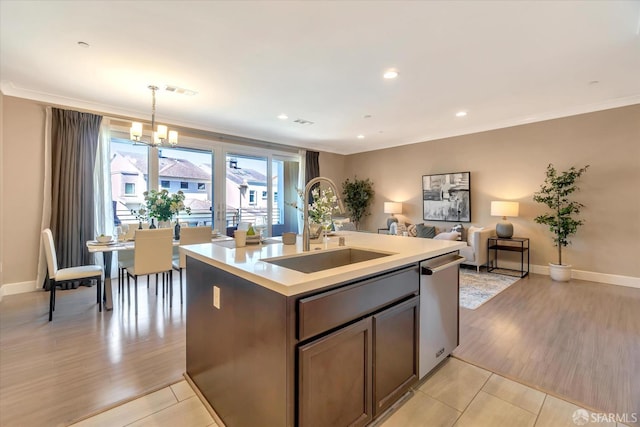 kitchen featuring pendant lighting, dishwasher, an island with sink, sink, and crown molding