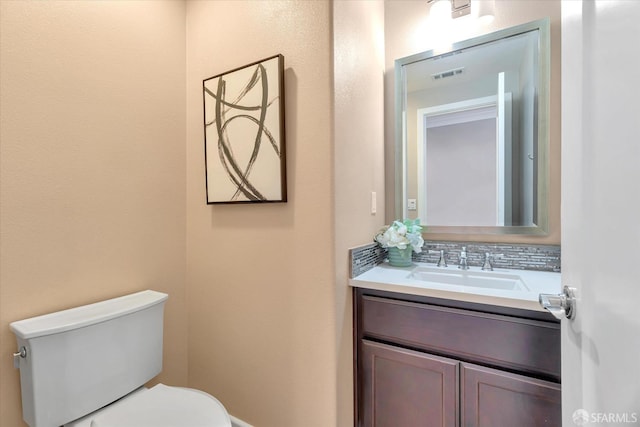 bathroom with toilet, tasteful backsplash, and vanity