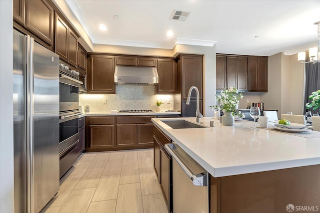 kitchen featuring sink, crown molding, a kitchen island with sink, and appliances with stainless steel finishes