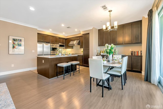 dining area with light hardwood / wood-style flooring, crown molding, and a chandelier