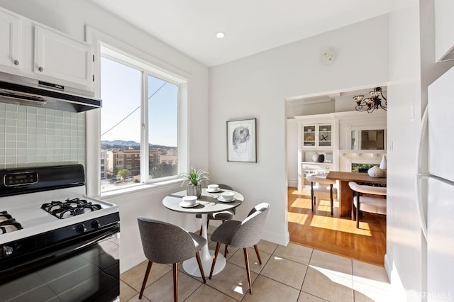 kitchen with white appliances, light hardwood / wood-style floors, tasteful backsplash, and white cabinets