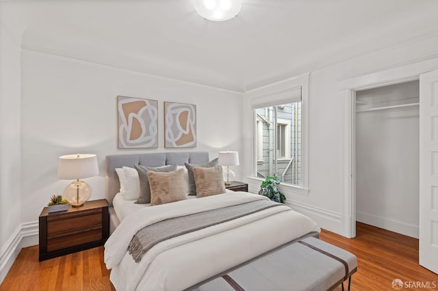 bedroom featuring ornamental molding, wood-type flooring, and a closet