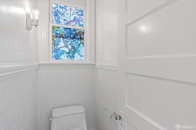 bathroom with toilet and tile walls