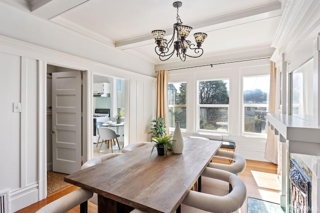 dining space featuring beamed ceiling, a chandelier, light wood-type flooring, and ornamental molding