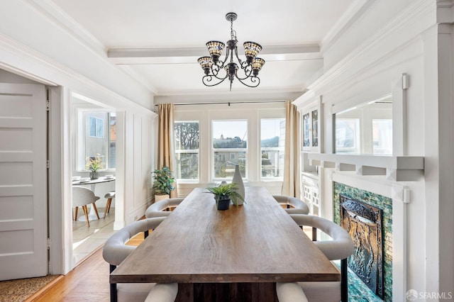 dining area featuring an inviting chandelier, light hardwood / wood-style flooring, beam ceiling, and crown molding