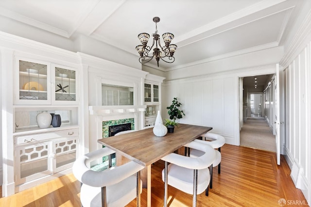 dining area featuring light hardwood / wood-style flooring, a premium fireplace, and an inviting chandelier