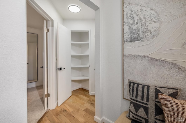 corridor with built in features and light hardwood / wood-style floors