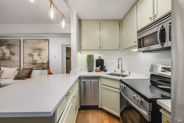 kitchen featuring appliances with stainless steel finishes, sink, pendant lighting, and kitchen peninsula