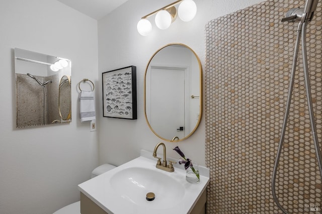 bathroom featuring vanity, tiled shower, and toilet