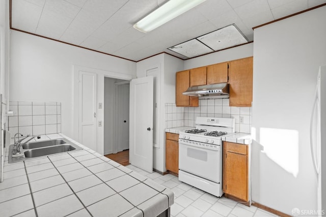 kitchen with backsplash, tile counters, white appliances, and sink