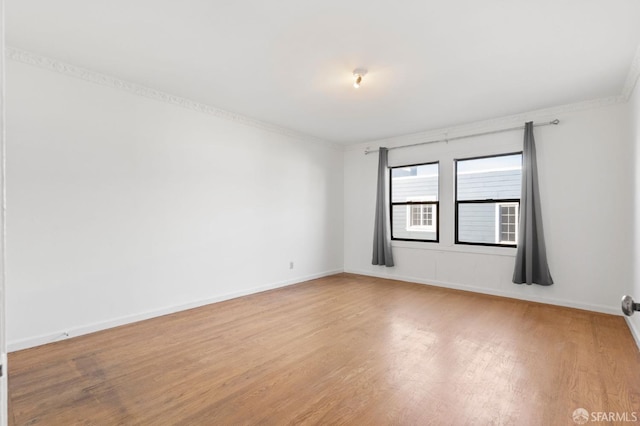 spare room featuring crown molding and light hardwood / wood-style floors