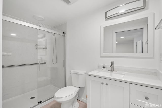 bathroom featuring vanity, toilet, and a shower with shower door