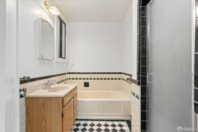 bathroom with a bathtub, vanity, and tile walls