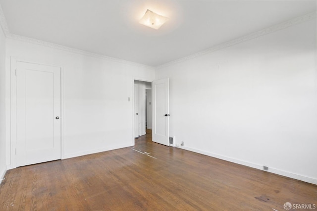 empty room featuring dark wood-type flooring and ornamental molding