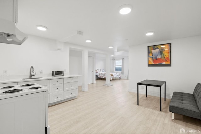 kitchen with white electric range, light hardwood / wood-style floors, white cabinetry, and sink