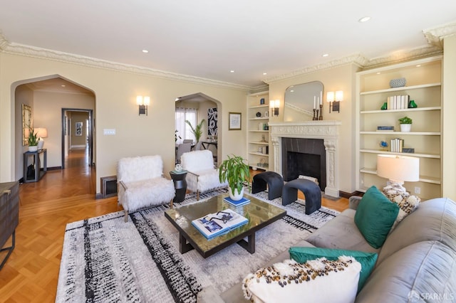 living room featuring ornamental molding, arched walkways, a high end fireplace, and recessed lighting