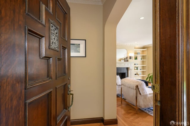 interior space featuring baseboards, a fireplace, arched walkways, and ornamental molding