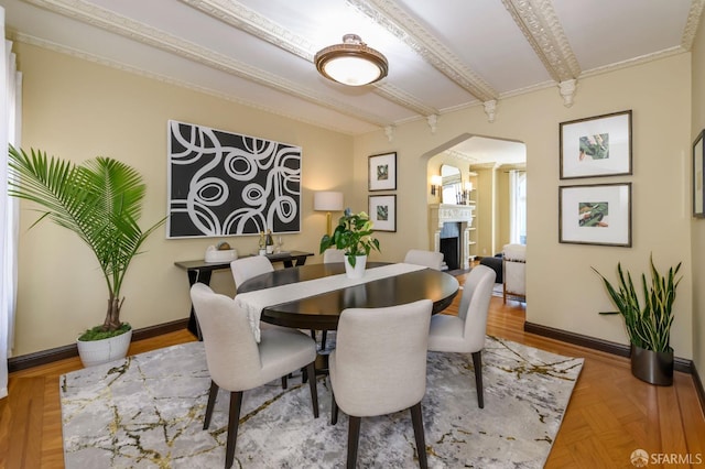 dining area with arched walkways, ornamental molding, a fireplace, and baseboards