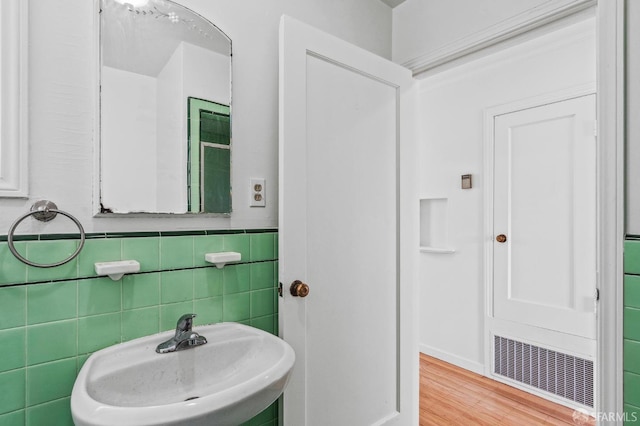 bathroom featuring hardwood / wood-style flooring, tile walls, and sink