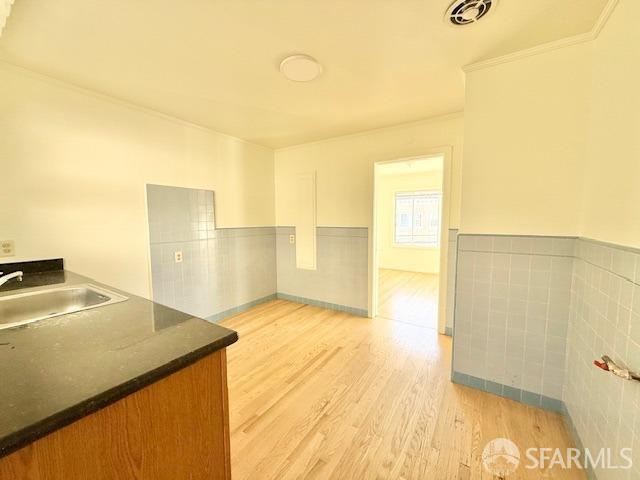 kitchen with crown molding, light wood-type flooring, and sink