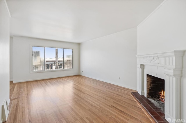 unfurnished living room featuring a tile fireplace, hardwood / wood-style floors, and crown molding