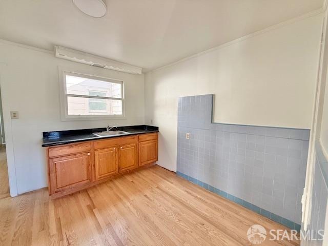 kitchen with light hardwood / wood-style floors, crown molding, and sink