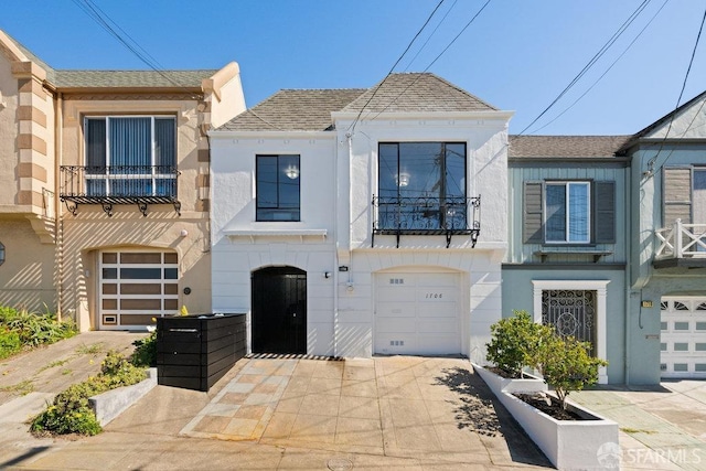 townhome / multi-family property featuring roof with shingles, driveway, a balcony, and an attached garage