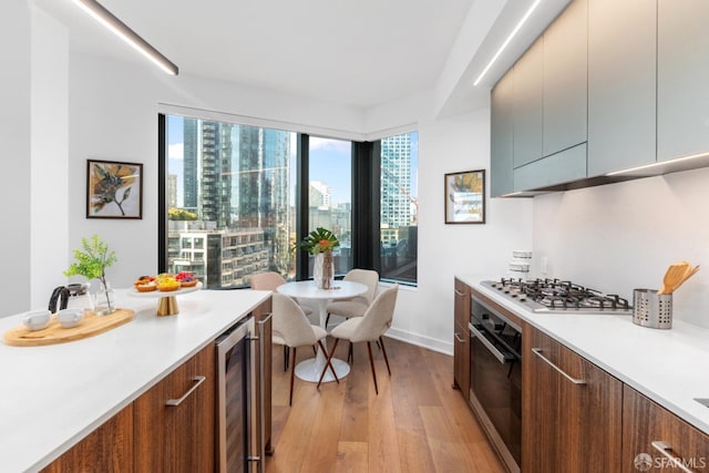 kitchen featuring wine cooler, appliances with stainless steel finishes, and light hardwood / wood-style flooring