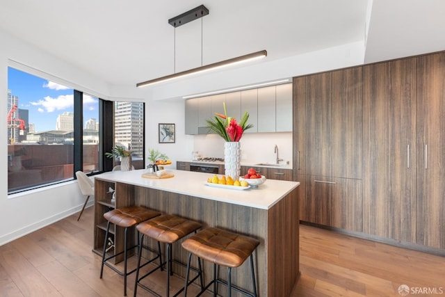 kitchen featuring light hardwood / wood-style floors, a center island, sink, a kitchen bar, and hanging light fixtures