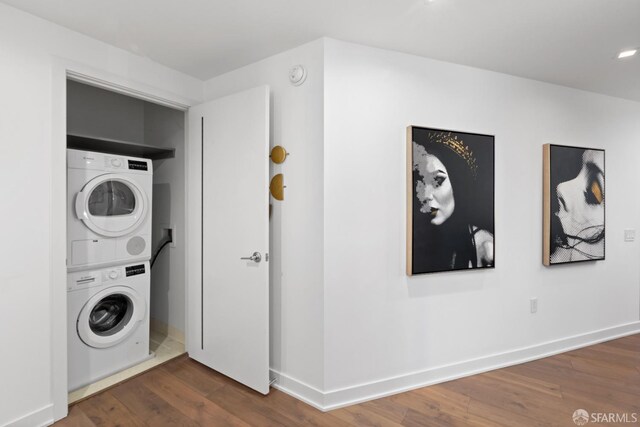 laundry area with dark hardwood / wood-style flooring and stacked washing maching and dryer