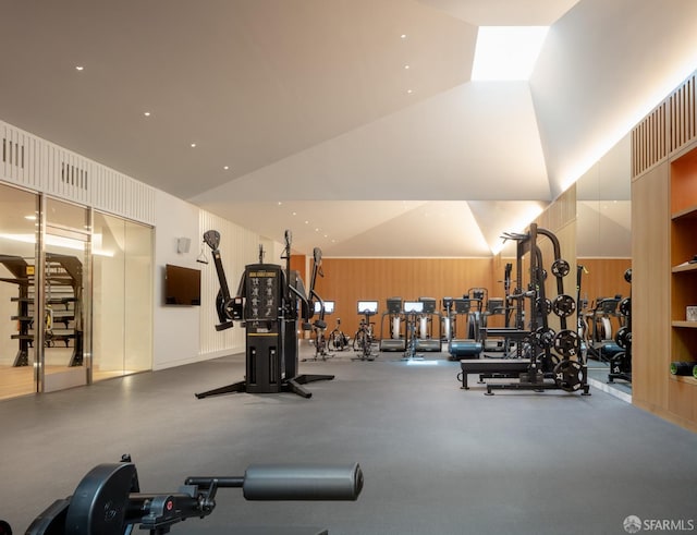 workout area featuring lofted ceiling and wooden walls