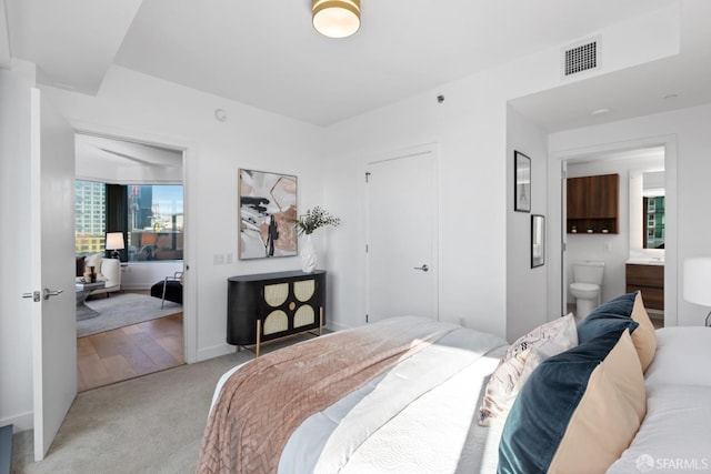 bedroom featuring light carpet and ensuite bath