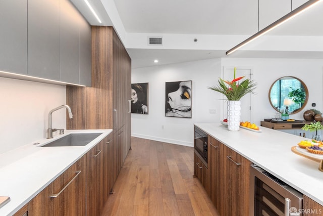 kitchen with black microwave, wine cooler, light hardwood / wood-style floors, and sink