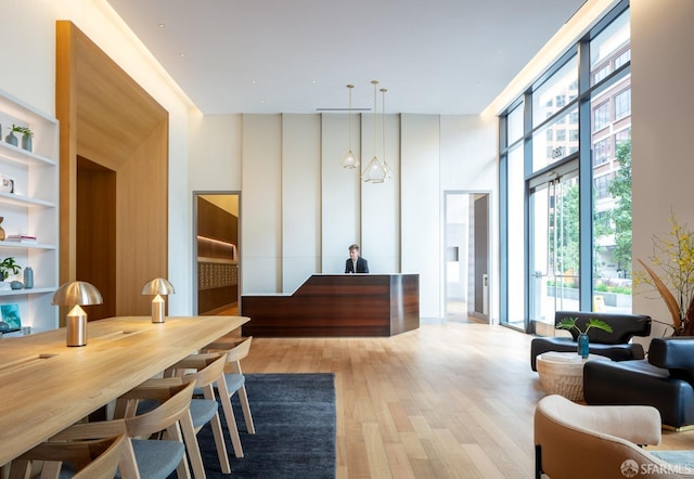 dining space with a towering ceiling, light hardwood / wood-style floors, and built in features