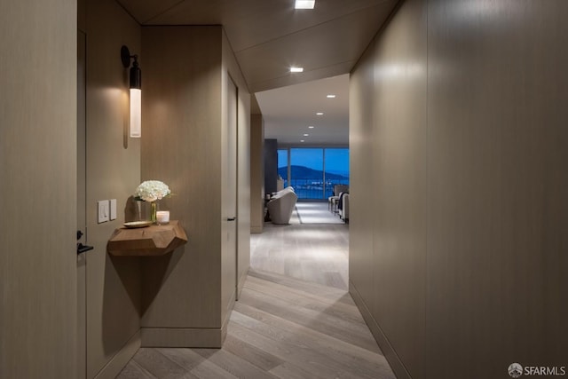 hall with floor to ceiling windows and light hardwood / wood-style flooring