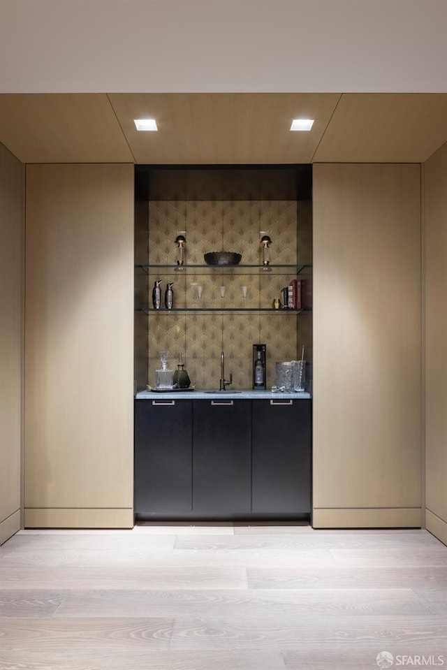 bar with sink and light hardwood / wood-style flooring